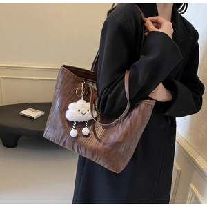 Détail du sac cabas marron foncé avec texture en cuir plissé et breloque nuage