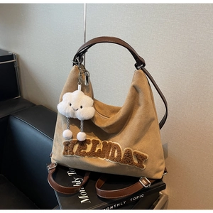 Gros plan du sac fourre-tout en daim camel avec broderie et breloque pelucheuse