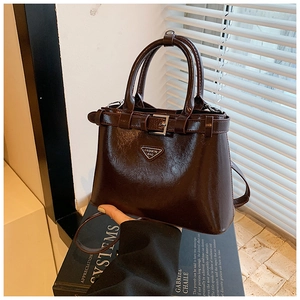 Détail du sac à main en cuir marron foncé avec logo en métal et boucle sur un support
