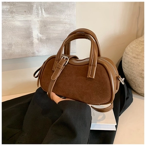 Detail of dark brown patchwork leather handbag with vintage suede texture and curved top