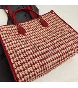 Macro shot of large red houndstooth tote bag with leather piping and gold buckle detail