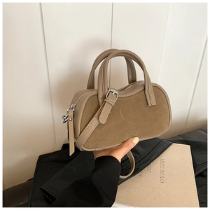 Detail of khaki suede patchwork pillow bag with embossed leather text and silver zipper