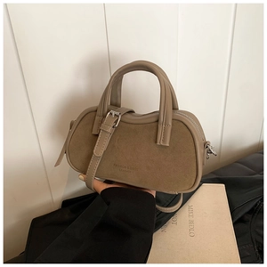 Macro detail of khaki leather patchwork bag featuring embossed logo and dual top handles