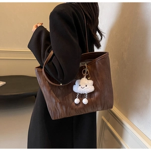 Détails de texture du cabas marron foncé avec gaufrage ondulé et breloque nuage en peluche