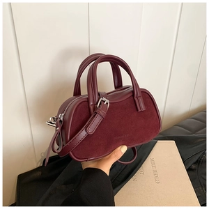 Detail of dark red textured leather boston bag showing dual handles and strap