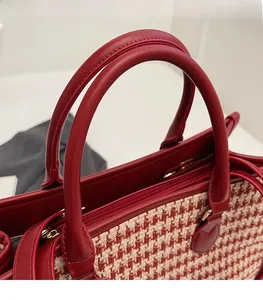 Detail of red tweed and leather bridal tote with round handles and gold zipper