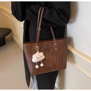 Détail d'un sac cabas marron foncé avec texture bois et charm nuage mignon