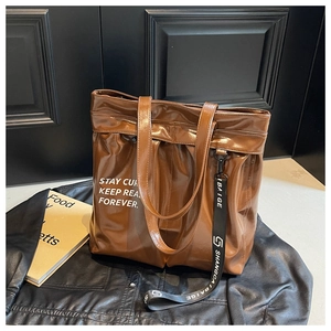 Close-up of brown faux leather tote bag with white text print and stylish bag charm