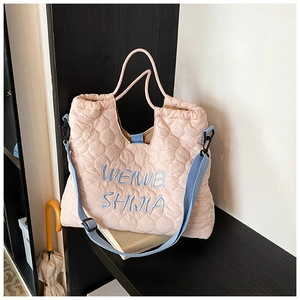 Close-up of pink quilted puffer tote bag with blue logo embroidery and adjustable strap