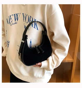 Detail of black suede hobo bag with silver zippers and smooth leather handle contrast