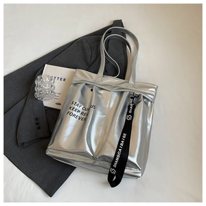 Detail of silver metallic tote bag with black motivational text and long decorative strap