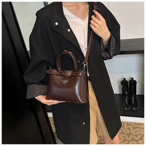 Détail d'un sac en cuir verni marron foncé avec logo triangulaire et bandoulière réglable