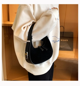 Detail of black matte leather hobo bag with silver hardware on model's shoulder