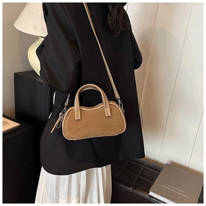 Detail of khaki suede mini pillow bag with top handles and shoulder strap on display