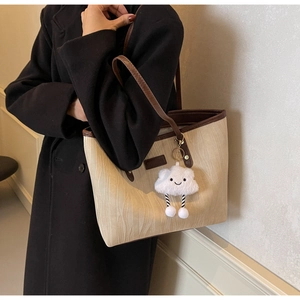 Détail d'un grand sac cabas en toile avec garniture en cuir marron et breloque nuage