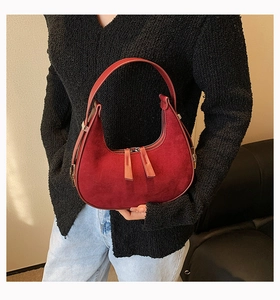 Detail of red suede hobo bag featuring matte texture and smooth leather handle finish