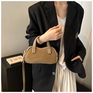 Close-up of a khaki suede crossbody bag with elegant top handles and embossed lettering