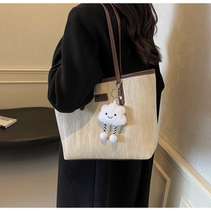 Gros plan du sac cabas crème avec texture ondulée et charm nuage porté à l'épaule