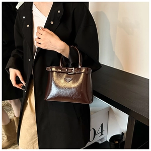 Détail du sac à main marron foncé en cuir verni avec boucle et plaque de logo