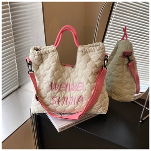 Detail of beige quilted tote bag with pink embroidery and adjustable wide shoulder strap