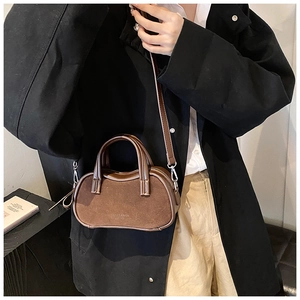 Brown mini crossbody pillow bag with textured leather stitching and elegant top handles