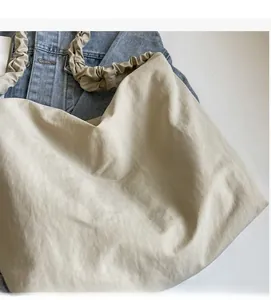 Detail of off-white large capacity tote bag featuring a unique scrunchie shoulder strap