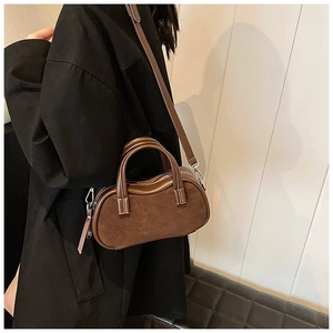Detail of a brown vintage texture crossbody bag paired with a black coat for women