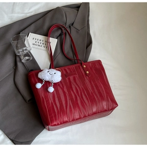 Détail du sac cabas rouge avec texture ondulée, rivets dorés et charm nuage