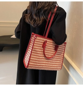 Detail of red houndstooth tote bag with dual straps on a model in a black coat