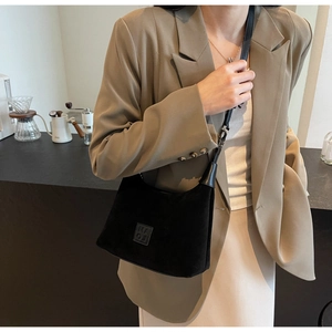Dettaglio della borsa a spalla in camoscio nero con logo indossata da una modella