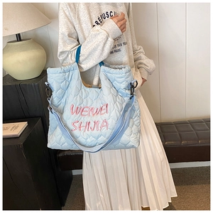 Light blue quilted tote bag with pink embroidery detail and comfortable shoulder strap
