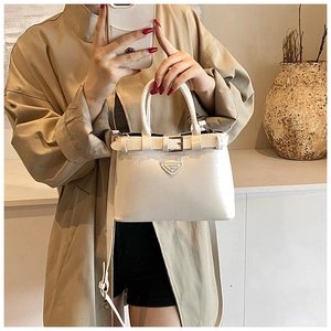 Détail du sac à main beige brillant avec boucle de ceinture et logo en métal tendance