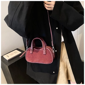 Detail of burgundy mini crossbody bag with textured leather and unique wavy edge design