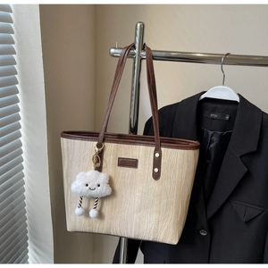 Détail du sac cabas beige texturé avec anses en cuir marron et pendentif nuage peluche