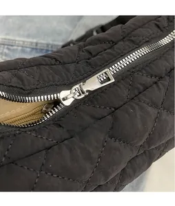 Détail de la fermeture éclair argentée sur le sac matelassé noir avec doublure marron doux