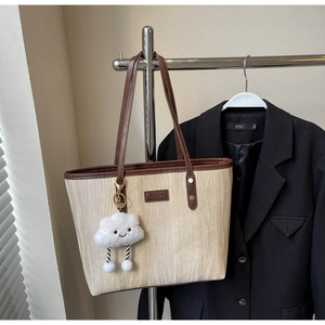 Détail du cabas beige avec texture ondulée, bordure en cuir marron et pendentif nuage