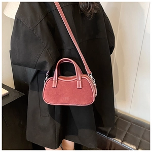 Detail view of wine red tote bag with suede texture and metal silver buckles worn by model