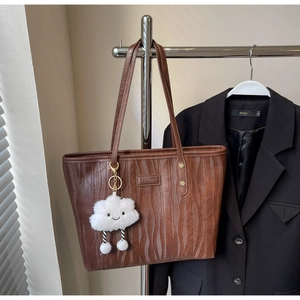 Détails de texture ondulée sur un sac cabas marron avec un charme nuage et des rivets