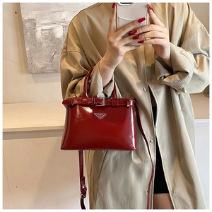 Détail d'un sac en cuir verni rouge montrant le fini brillant et le logo triangulaire