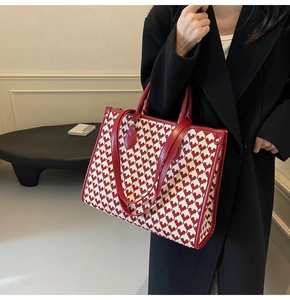 Macro shot of large red pixel heart tote bag with leather straps on a model