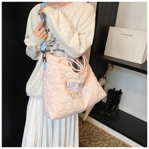 Detailed close-up of quilted pink tote bag with blue embroidery and drawstring closure