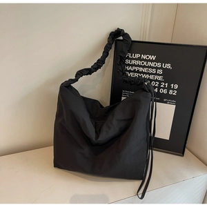Detail of hobo shoulder bag with pleated strap and side drawstring on marble surface