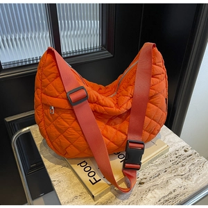 Détail du sac à bandoulière matelassé orange avec motif de losanges et sangle