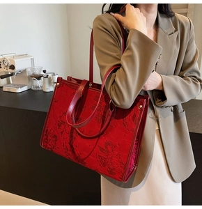 Detail of red bridal tote bag with floral jacquard texture and golden hardware accents