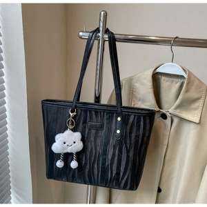Détail d'un sac cabas noir à texture ondulée et d'un pendentif nuage blanc