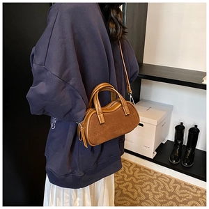 Detail of a brown suede Boston bag showing texture and stitching in a lifestyle setting