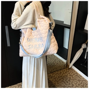 Detail of pink quilted tote bag with heart patterns and blue embroidered letters
