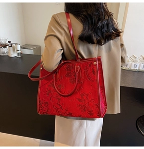 Close-up of red floral jacquard tote bag with leather straps and metal rivets