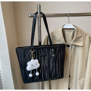 Détail du sac cabas noir texturé à rayures avec une breloque nuage en peluche blanche
