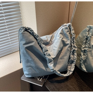 Detail of light blue cloud-shaped shoulder bag featuring elegant pleated strap design